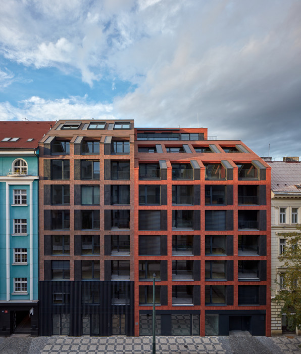 Bytový dům je rozdělen na dvě části, dva domy. Toto hmotové členění vychází z původní parcelace pozemku. Také to respektuje strukturu městského bloku, kde se střídá výška střech a říms.