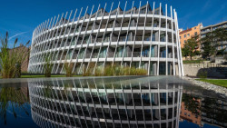 Prosklený sokl, kde jsou kanceláře a obchody plus expresivní pětipatrová věž. Byty jsou od rušné Holečkovi ulice v Praze odděleny skleněnou stěnou. Ateliér DAM architekti, realizace 2022