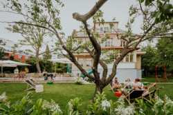 Můžete se tu posadit u stolu pod slunečníkem, jen tak na trávu nebo do lehátka. Kolem vás cinká porcelán a smějí se děti, které si hrají na trávníku. (Vila 63, edit!)