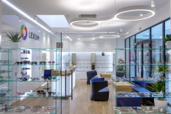 Bílá barva a sklo byly doplněny přírodním dekorem dřeva. Optika CORNEA LEXUM v Praze.