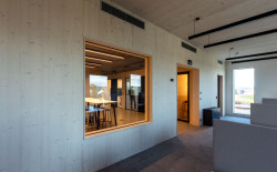 Velká okna zajišťující přirozené osvětlení, v kombinaci s dřevěnými prvky, pozitivně ovlivňují náladu i produktivitu.