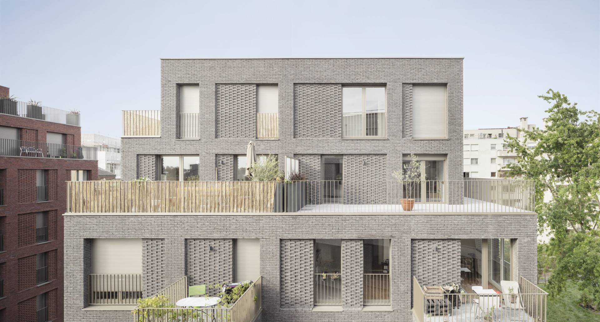 Studio AVENIER CORNEJO architectes navrhlo na břehu kanálu na předměstí Paříže obytný soubor třech domů s různým odstínem lícových cihel