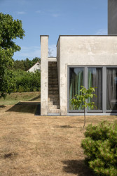 Na střešní terasu vedou dvě úzká schodiště zapuštěná v hranách spodní části domu.