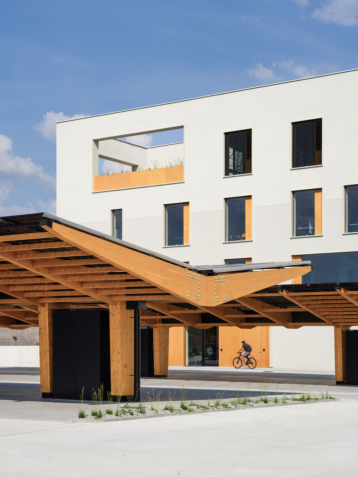 Přístřešky na parkovišti kryjí. (Kanceláře postavené z CLT panelů; Studio Perspektiv)