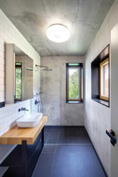 Celý interiér je světlý a jemný, toho autoři docílili také zvoleným materiálem. Celá chata je vybarvená světlými tóny šedé, dřevěnou podlahou a betonovými povrchy s přiznaným bedněním. (Chata v Posázaví, Studio Sporadical)