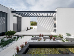 Dům má uprostřed dispozice atrium, kde mezi bílými oblázky prorůstá zeleň a vyvěrá pramen. (Vila u Prahy, boq architekti)