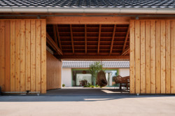 V hlavním objektu se bydlí a v tom druhém parkují auta, kola a zároveň funguje jako zastřešené venkovní sezení. 