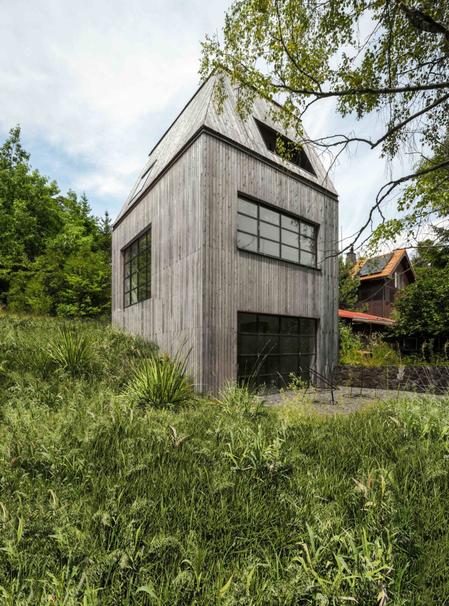 Stavba vertikální formy je umístěná v prudkém svahu tak, aby nebyl zásah do terénu v místě téměř patrný. (Chata JARO u Prahy, edit! architects)