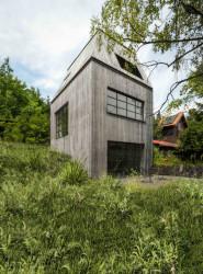 Stavba vertikální formy je umístěná v prudkém svahu tak, aby nebyl zásah do terénu v místě téměř patrný. (Chata JARO u Prahy, edit! architects)