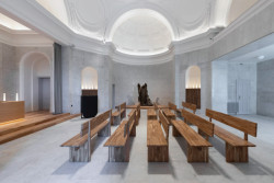 Kontrast mezi studeným kamenným obkladem a teplým dřevem (Rekonstrukce obřadní síně na Olšanských hřibitovech; Ateliér Schwestern)