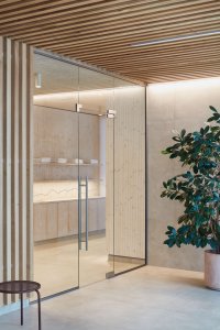 Wellness centrum lázní Aurora v Třeboni, Plus One Architects: Použily béžové dlaždice, drcený kámen a dřevo.