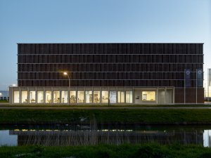 Městský Archiv Delft, Office Winhov, Gottlieb Paludan Architects: Noční pohled se svítícím parterem kavárny a čítáren