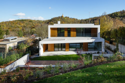 Výhled z nejvyšší úrovně zahrady na vilu Block House s kostelem sv. Matěje v pozadí (Block House v Šáreckém údolí v Praze; Studio MA)