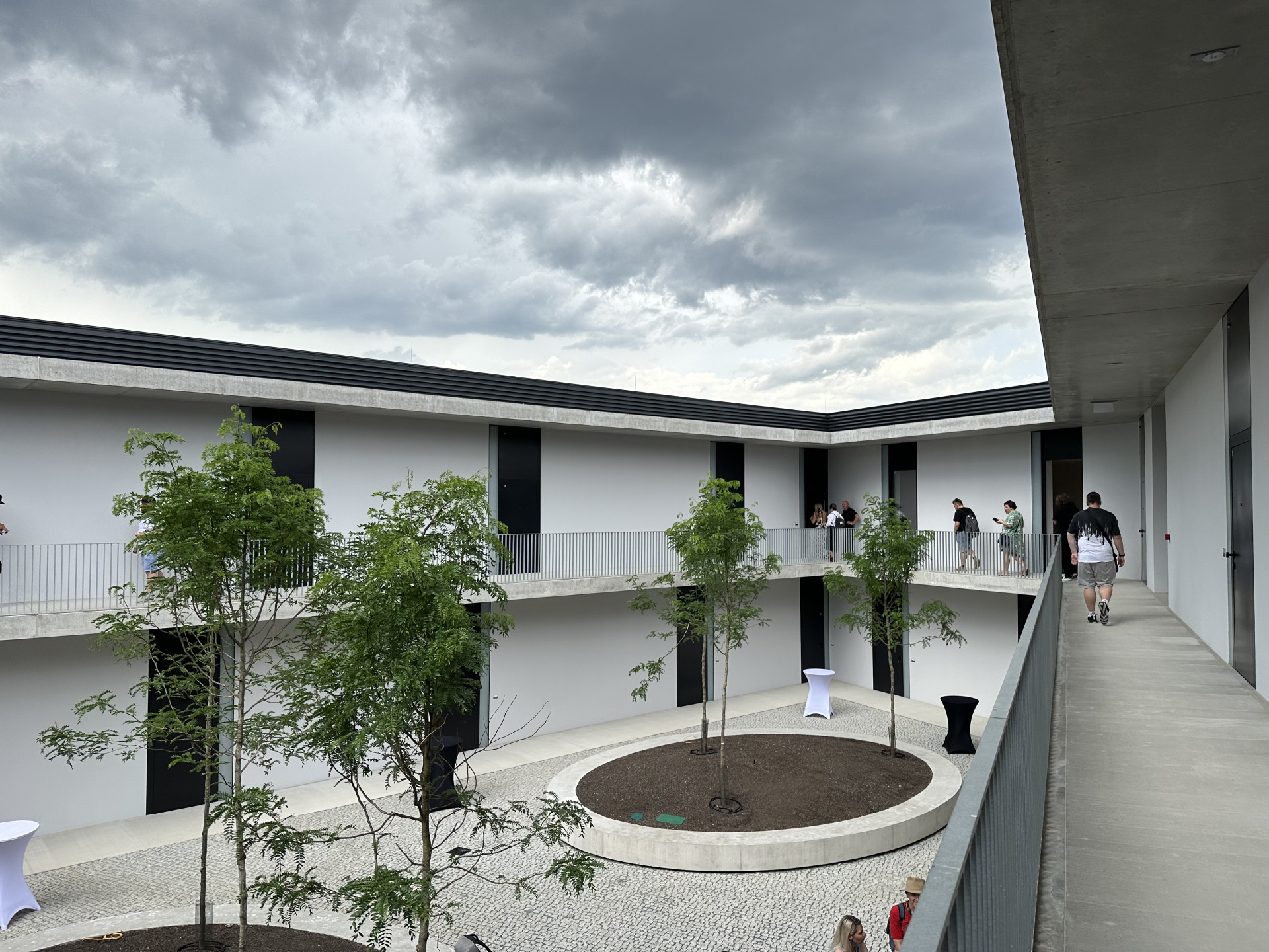 Nový bytový dům – ten s tmavou fasádou – má uvnitř atrium, byty jsou přístupné z pavlače.