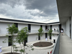 Nový bytový dům – ten s tmavou fasádou – má uvnitř atrium, byty jsou přístupné z pavlače.