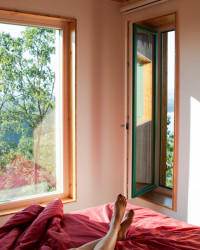 Ložnici vládne červená postel s bavlněným povlečením a bílé zdi. 