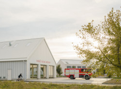 Velká bílá stavba slouží pro auta a techniku. (Hasičská stanice Dolní Jirčany, SOA architekti)
