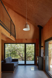 Jednolitost materiálu rozbíjejí velké průhledy ven. (Chata v Posázaví, Atelier Hajný)