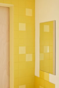 Detail žlutých obkladů v koupelně. (Byt pro malířku v Praze-Holešovicích od Plus One Architects)