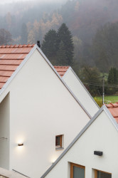 Tři domy měřítkem podobné menším stavením kolem