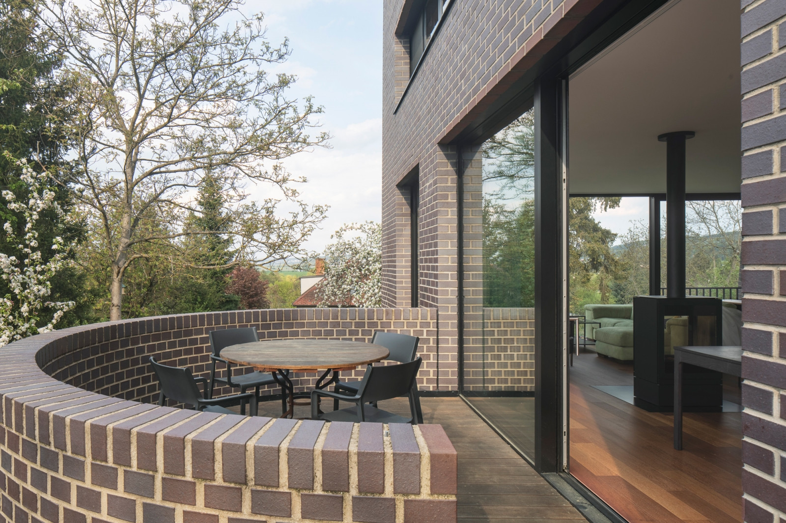 Motiv ozvláštnění do realizace vnáší také nízký půlkruhový rizalit, jakási apsida, na níž vznikla terasa přístupná z obývacího pokoje