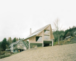 Dům ve svahu, AMUNT Nagel Theissen: Vyvýšení nad terén pomocí systému betonových podpor chrání dřevostavbu před deštěm a sněhem