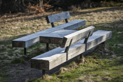 Lavice s opěrkou a stolem z masivního dubového dřeva usazené na zemních vrutech.