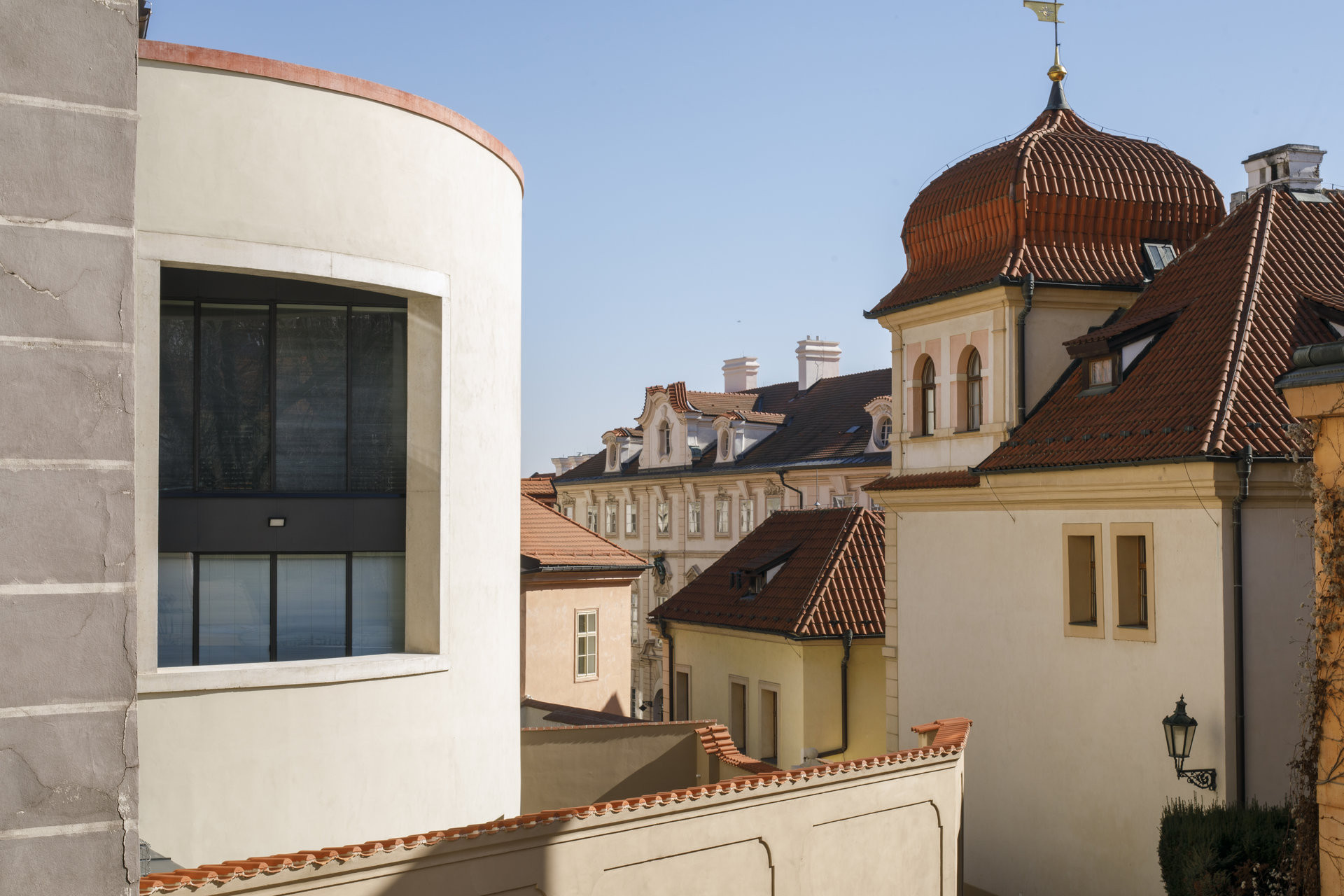 Zaoblení stavby reaguje na nepravidelnou stopu původní obvodové zdi i tvar slepé uličky Tržiště. (Bytový dům na Malé Straně; architektonický ateliér Ladislava Lábuse)