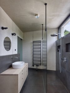 Jednoduchý koupelnový interiér – beton a šedé obklady (Vila Troja, Stempel & Tesar architekti)