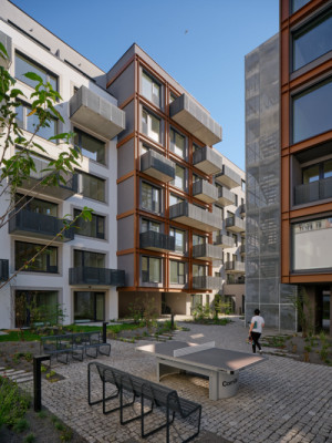 Za městskou fasádou se otevírá klidný zelený vnitroblok, který kontrastuje s industriálním výrazem domu. (MiDO Harfa; QARTA Architektura)
