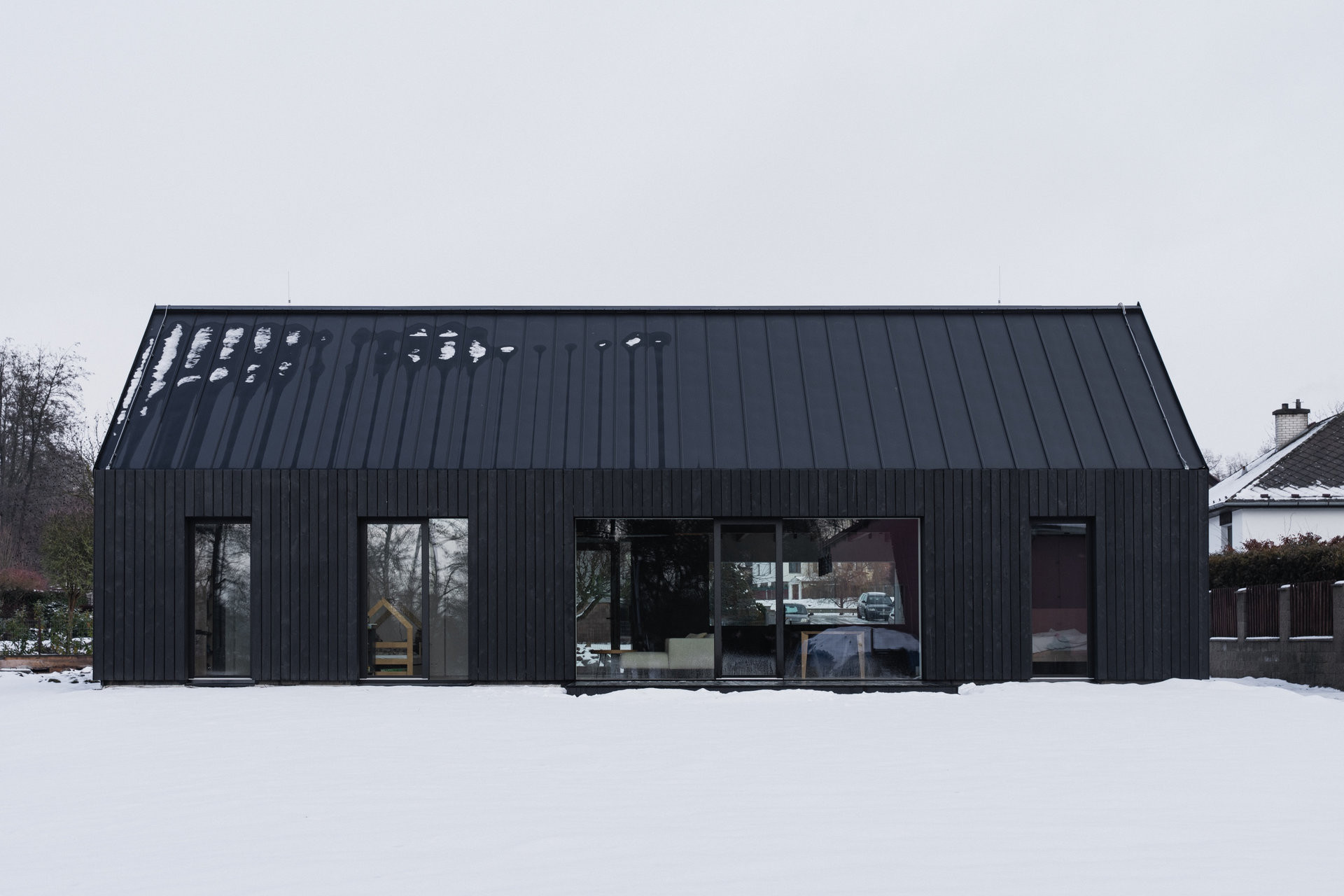 Vyjít na zahradu lze z obývacího pokoje i ložnice. (Přízemní dům s fasádou z opalovaného dřeva; Luni architekti)