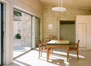 Konverze starého statku, Martin Migeon Architecture: Interiér hraje barevnou škálou světlých odstínů betonu, kamene a překližky v kombinaci se starým dřevěným nábytkem.