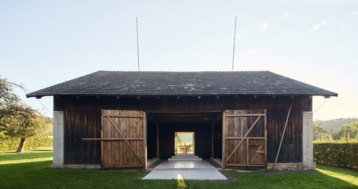 Průhled stodolou a rozvinutý betonový "koberec". (Krabice ve stodole; Facha architekti)