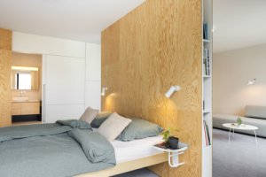 Interiér pracuje s akustickými panely, HPL deskami a březovou překližkou. (Bytový dům od KOMA MODULAR)