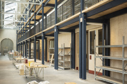 Lehká dřevěná konstrukce ošetřená směsí oleje a regionálního indiga vymezuje prostor galerie (Rekonstrukce bývalých železničních dílen; ASSEMBLE, Atelier Luma, BC Architects )