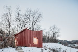 Chata v Sušici, BYRÓ architekti: Směrem dolů ze svahu ji modeluje prohnutá střecha, která navazuje na úroveň sousední chatové zástavby
