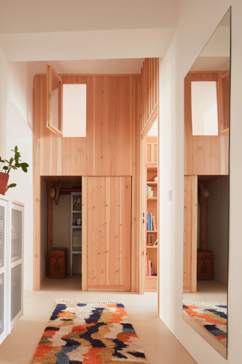 Kumbál na věci a nad ním okénko z dětského pokoje. (Plus One Architects, byt ve Vršovicích)