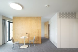 Interiér pracuje s akustickými panely, HPL deskami a březovou překližkou. (Bytový dům od KOMA MODULAR)