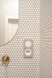 Bílý obklad doplňují mosazné baterie a niky s betonovými deskami. (rekonstrukce prvorepublikového bytu v Bubenči, Studio COSMO)