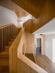Rekonstrukce řadového domu u letiště, No Architects: Nové schodiště ze dřeva s výrazným řemeslným detailem svou dimenzí a opakujícím dekorem dodává celému interiéru jasnou tvář