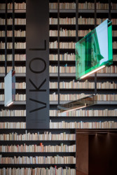 Obnova Červeného kostela, atelier-r: Rozsáhlé stěny vyplněné starými knihami otočenými hřbety dozadu s večerním podsvícením