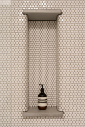 Bílý obklad doplňují mosazné baterie a niky s betonovými deskami. (rekonstrukce prvorepublikového bytu v Bubenči, Studio COSMO)