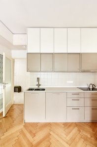 Kuchyň je uspořádána podél jedné stěny jako v původním řešení. (Rekonstrukce bytu na Vinohradech, Markéta Bromová architekti)
