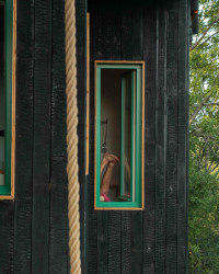 Černou barvu páleného dřeva na fasádě doplňují barevné rámy oken.