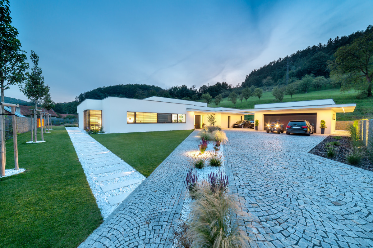 Garážové stání pro dva automobily, které se nachází mezi domem a samostatnou dvojgaráží na východní straně, je kryto výraznou železobetonovou moniérou. (Villa Všemina; Kareš Arch)
