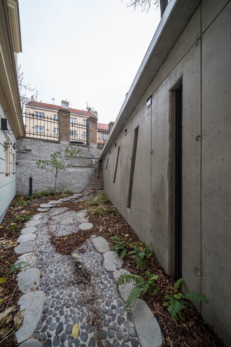 Podél kaple se vine symbolické koryto, které za deště naplňuje voda stékající ze střechy. (Kaple v Praze-Záběhlicích; JIRSA – ARCHITEKTI)