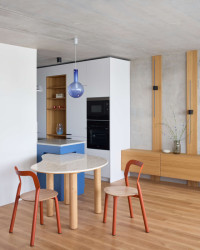 Modré odstíny se v různých podobách objevují na kuchyni, knihovně nebo svítidlech, pokaždé trochu jiné, a vytvářejí tak nenápadnou vizuální linku. (Panelákový byt Nad obzorem; Iva Hájková Studio)