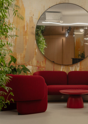 Kulaté zrcadlo nad pohovkou odráží dřevěný obklad recepce a rozšiřuje úzký prostor lounge. (Kanceláře JSK v Praze; BekArch)