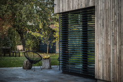 Rodinný dům v Písnici, daviddavidová architekti: Přístavba je opláštěná dřevěným, vertikálně kladeným obkladem z nehoblovaných a neošetřených modřínových prken