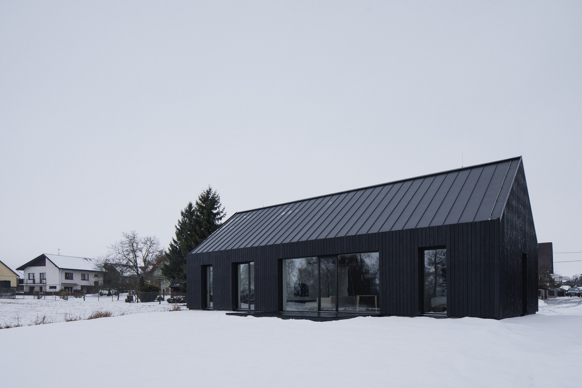 Dům je velkými prosklenými plochami propojený se zahradou. (Přízemní dům s fasádou z opalovaného dřeva; Luni architekti)